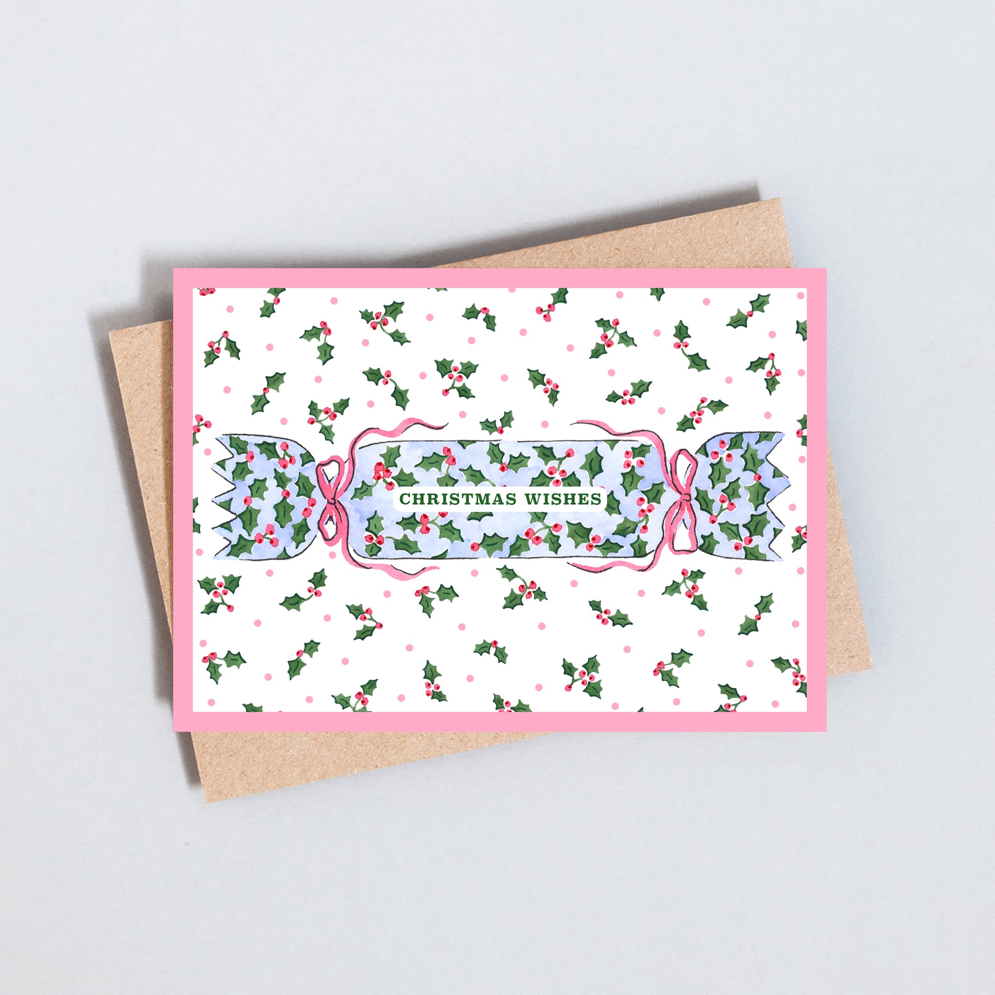 Christmas card featuring a traditional cracker decorated with holly, pink bows and Christmas Wishes lettering.