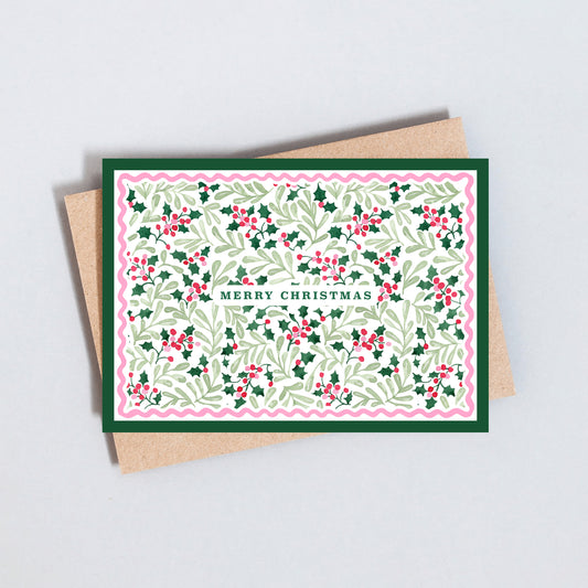 Traditional Merry Christmas card featuring an illustrated holly leaf and berry pattern with decorative scalloped border.