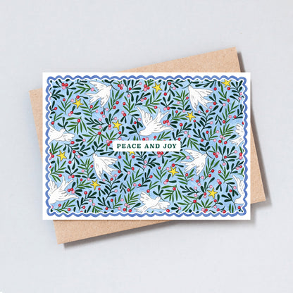 Illustrated Peace and Joy Christmas card featuring white doves, evergreen foliage, winter berries and golden stars on a soft blue background.