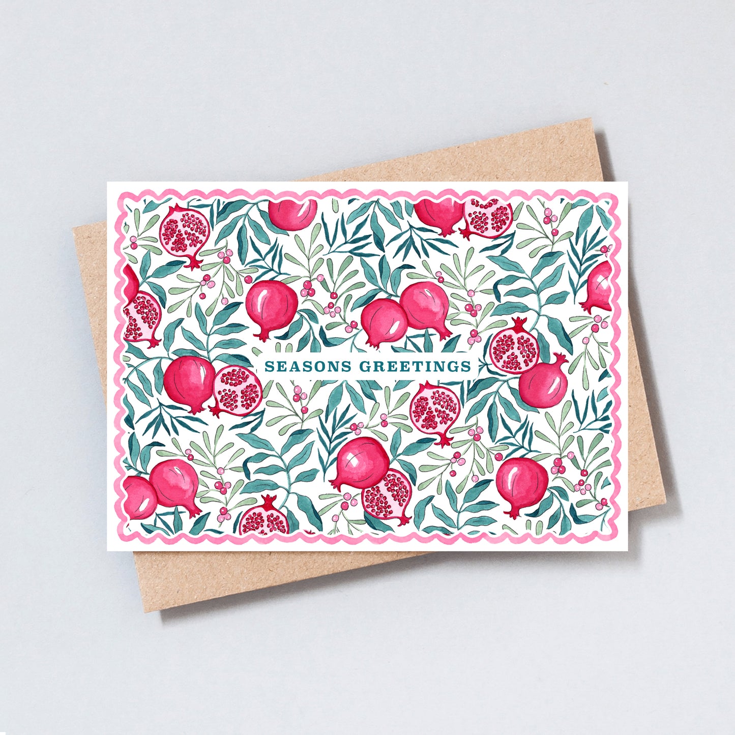 Illustrated Seasons Greetings Christmas card featuring hand-painted pomegranates, winter foliage and berries with a pink scalloped border.