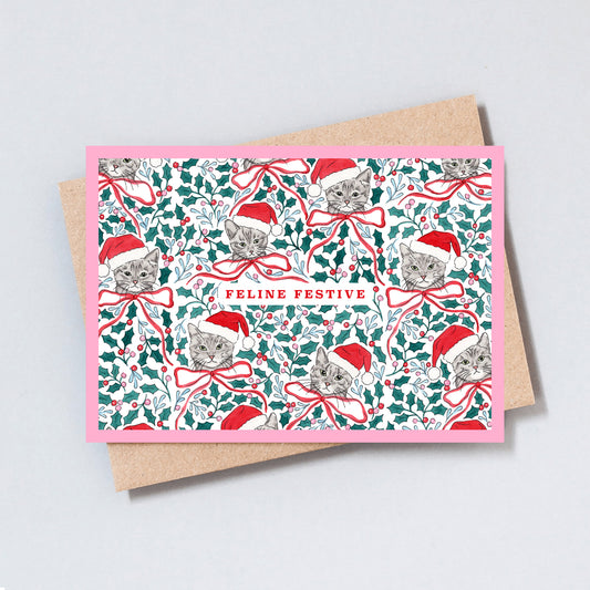 Illustrated Christmas card featuring cats wearing Santa hats amongst holly, festive foliage and ribbon bows with the words Feline Festive.