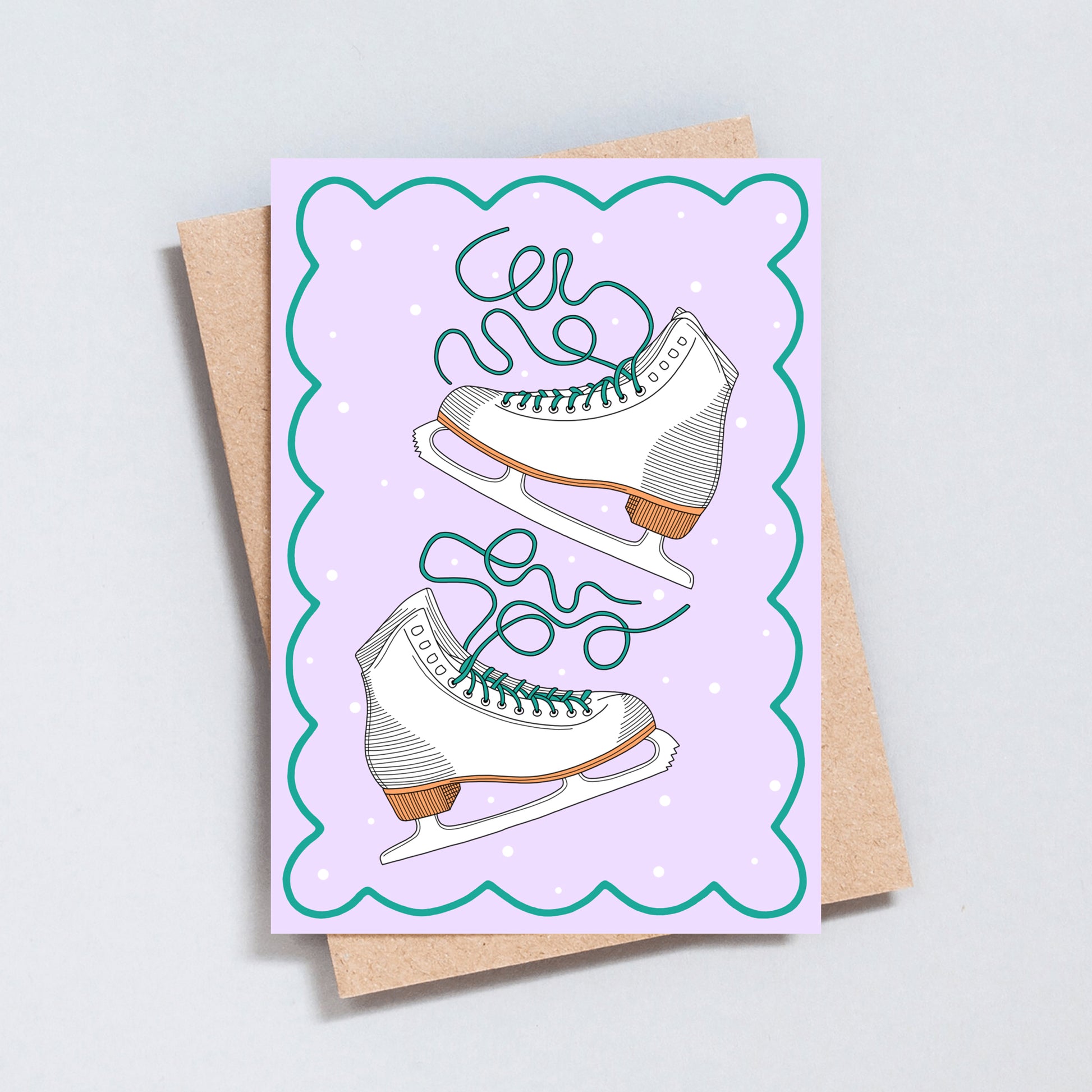 Hand illustrated Christmas card featuring white ice skates with green laces on a lilac background with scalloped edges.