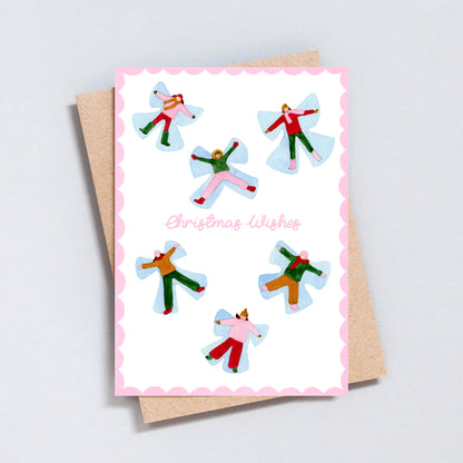 Hand illustrated Christmas card featuring playful snow angels and the words “Christmas Wishes”, printed on hammered 300gsm card with a pink scalloped border.