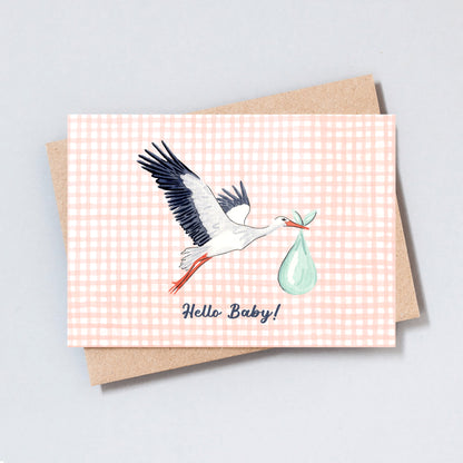 Hand-drawn stork carrying a baby bundle with the text “Hello Baby!” on a peach gingham background.