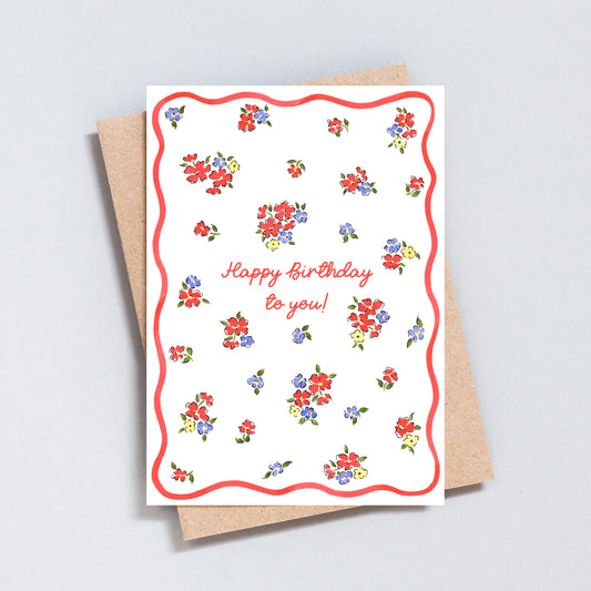 Minimal floral birthday card with scattered colourful flowers, pink script lettering and pink wavy border