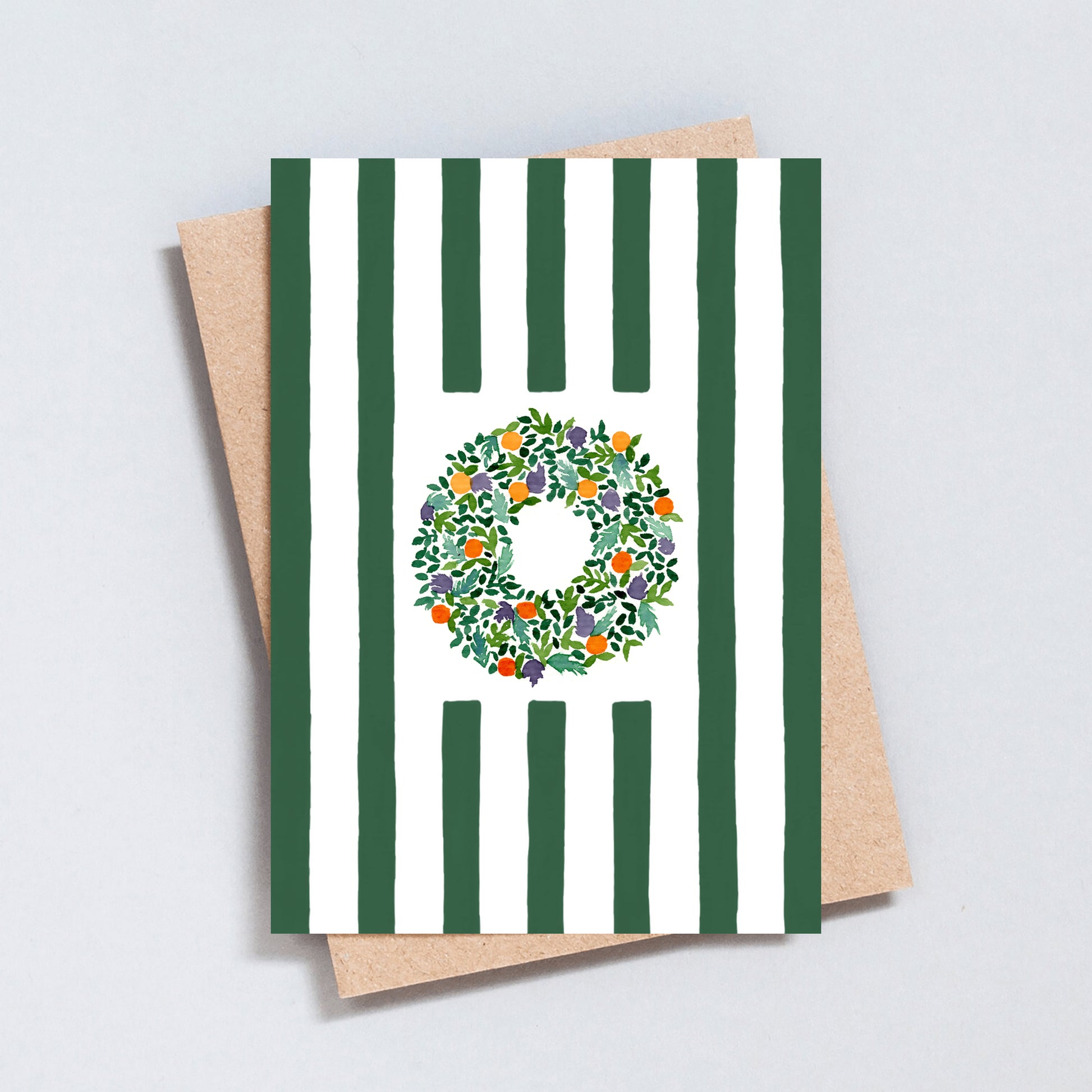 Hand illustrated Christmas card featuring a festive wreath on green and white stripes, printed on hammered 300gsm card.