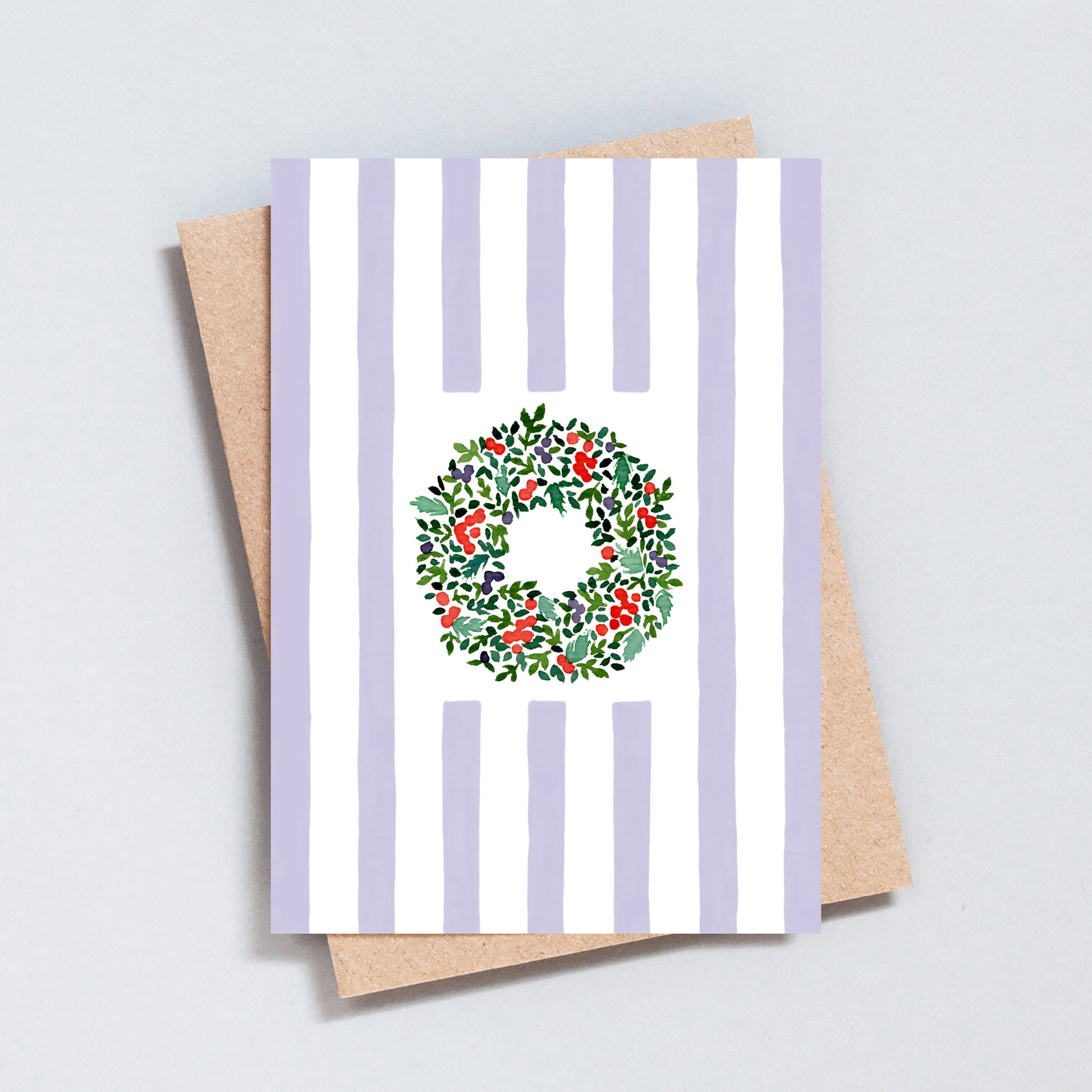 Hand illustrated Christmas card featuring a festive wreath on green and white stripes, printed on hammered 300gsm card.