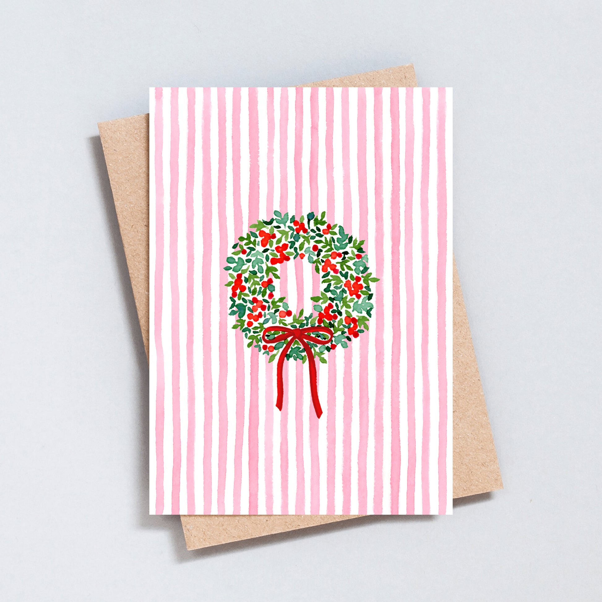 Pink striped Christmas card with hand-painted holly wreath and red bow, designed by The Type Club