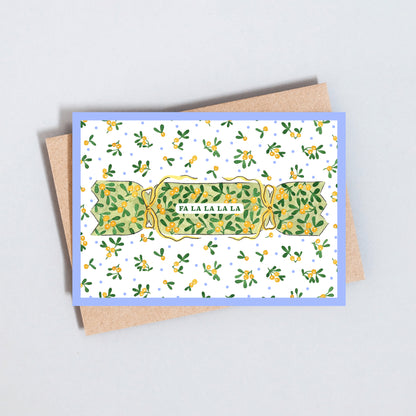 Illustrated Christmas card featuring a traditional Christmas cracker with festive greenery and Fa La La La greeting on textured white card.